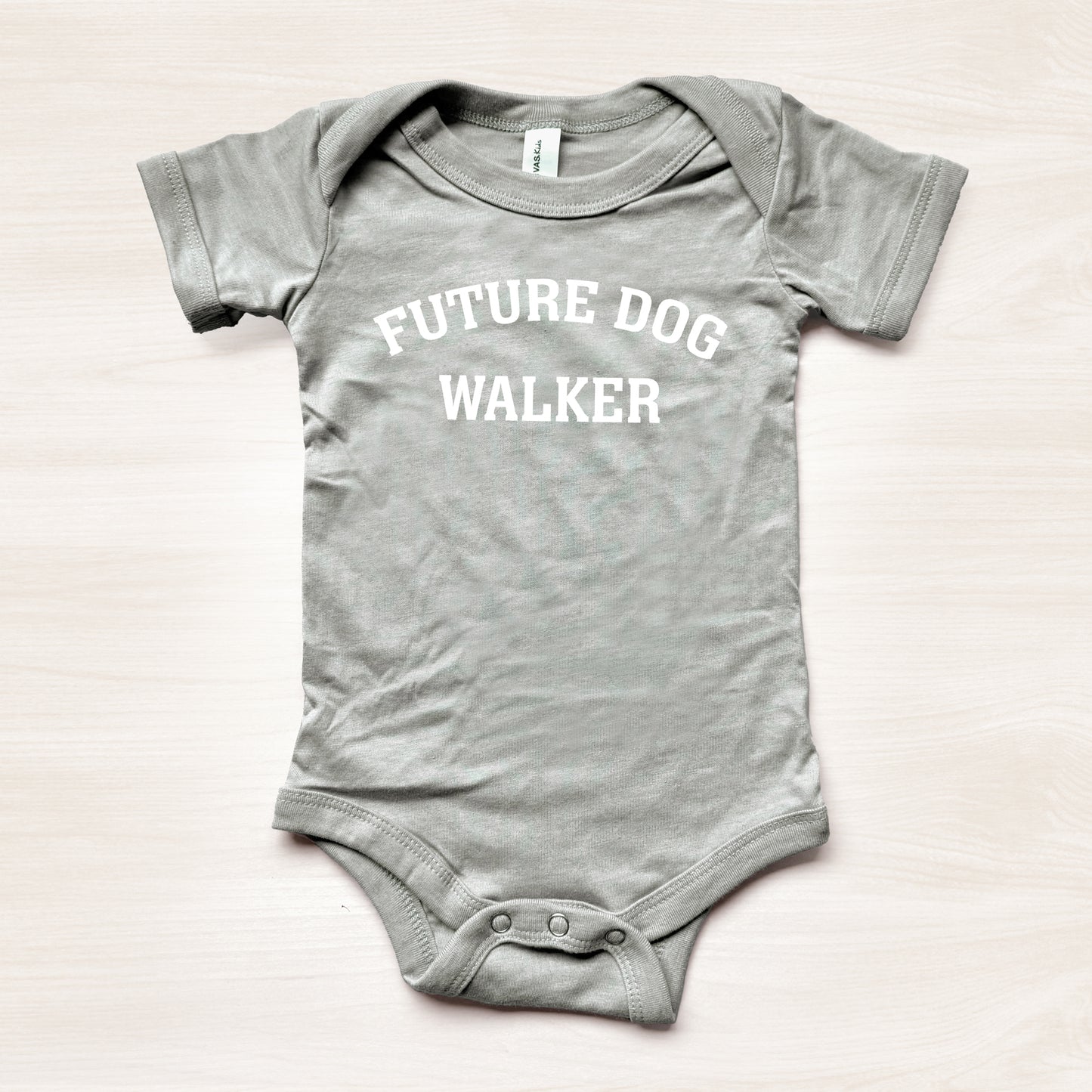 Gray baby onesie with 'Future Dog Walker' text on a light background
