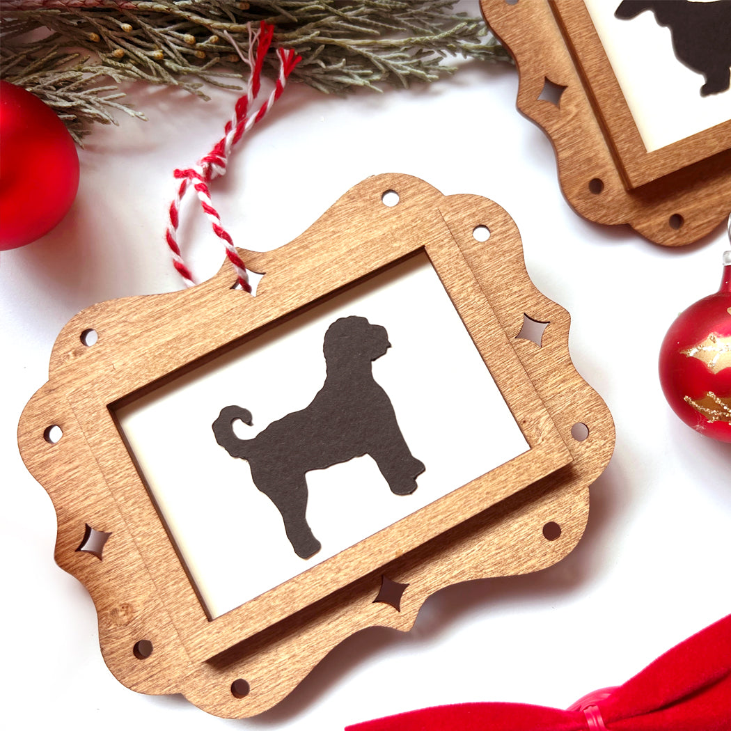 Wooden ornament with dog silhouette on a white background with Christmas decorations.