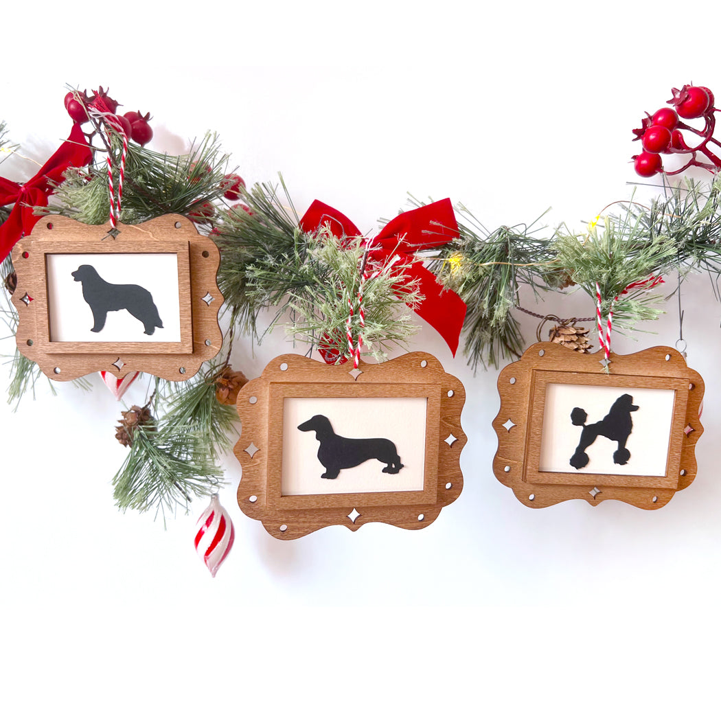 Three wooden picture frames with dog silhouettes on a Christmas-themed background with garland and ribbons.