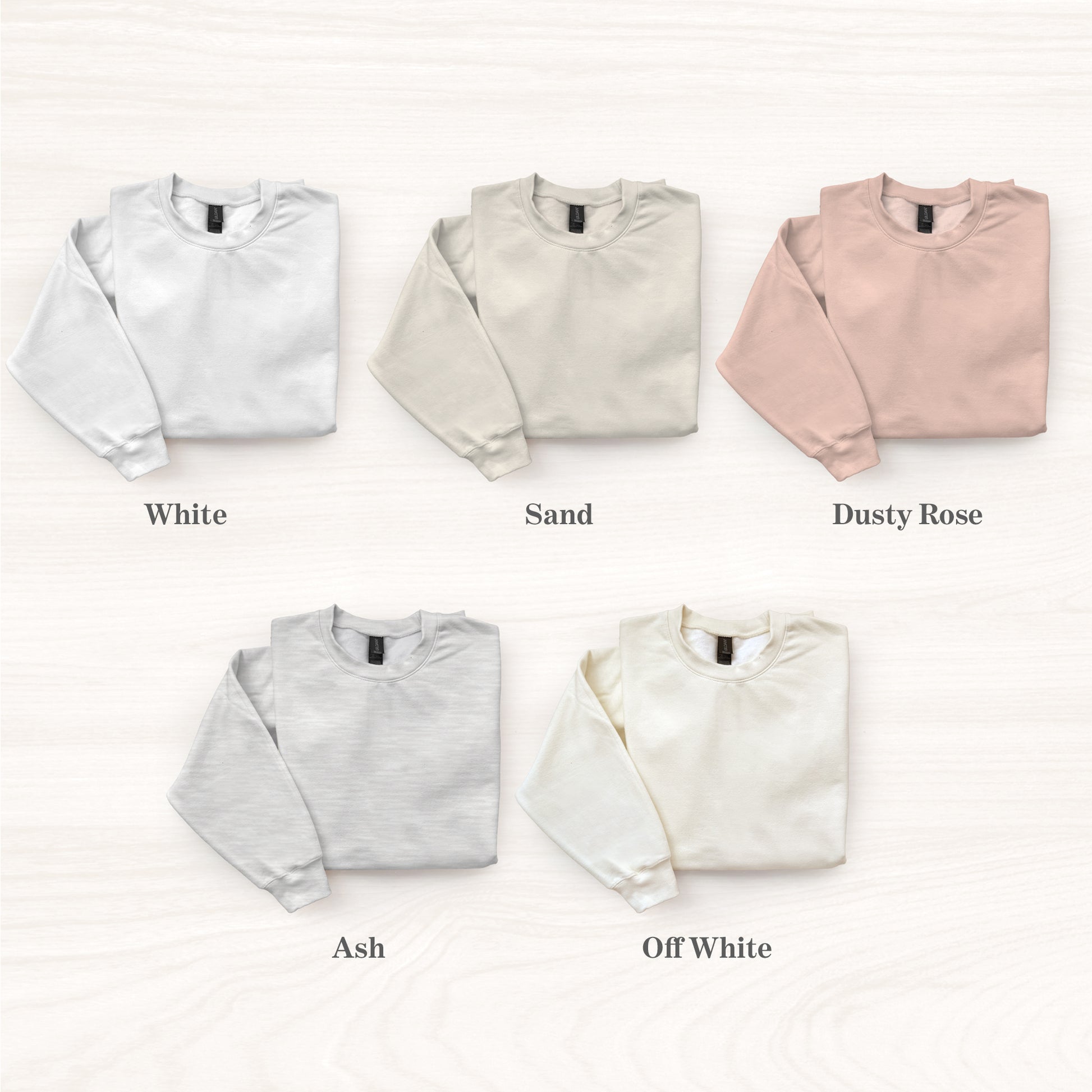 Five folded sweatshirts in different colors on a white background