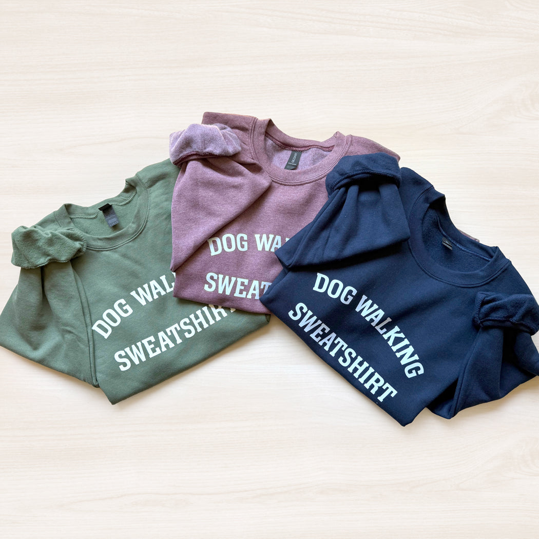 Three sweatshirts in green, maroon, and navy with 'DOG WALKING SWEATSHIRT' text on a light background.