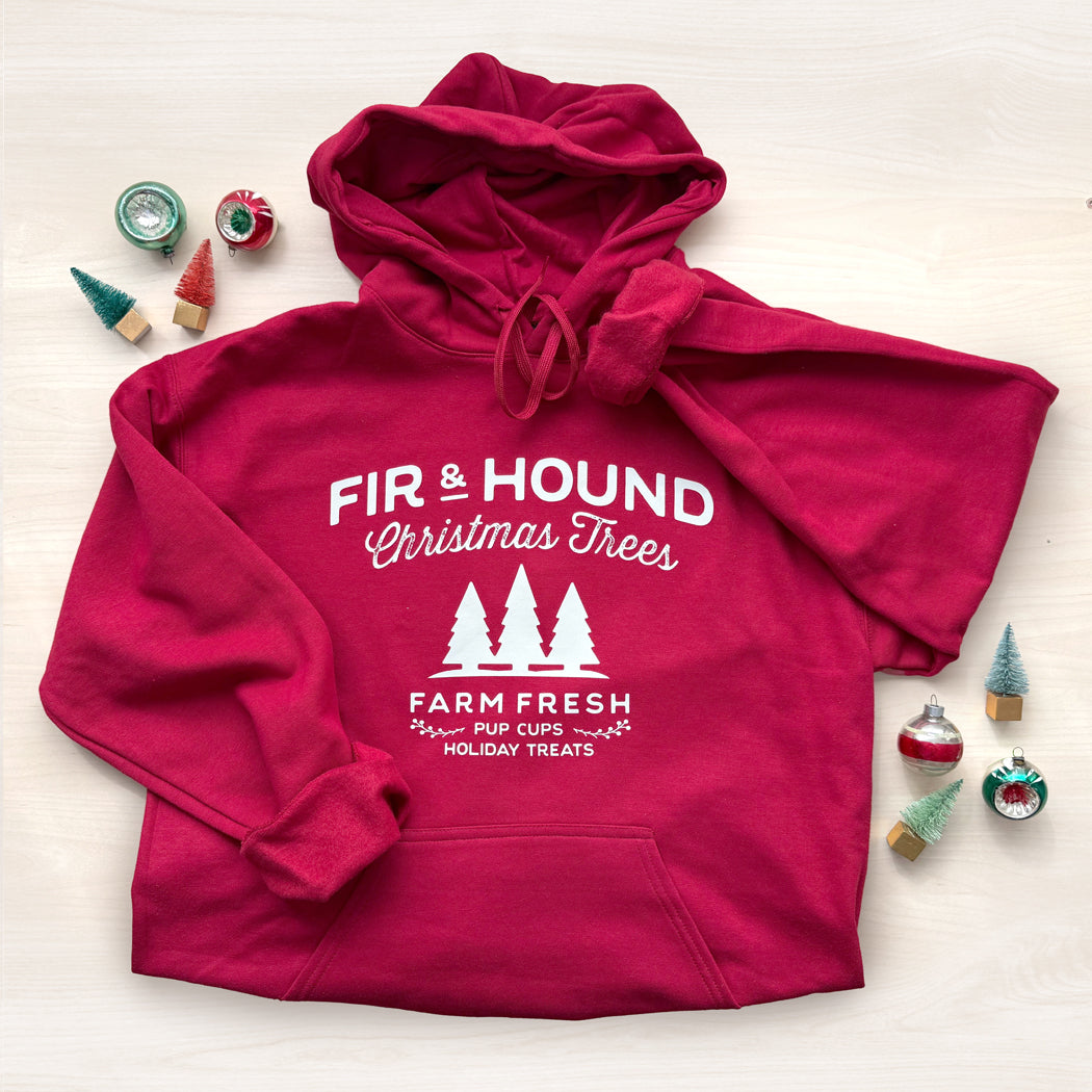 Red hoodie with 'Fir & Hound Christmas Trees' text with Christmas decorations.