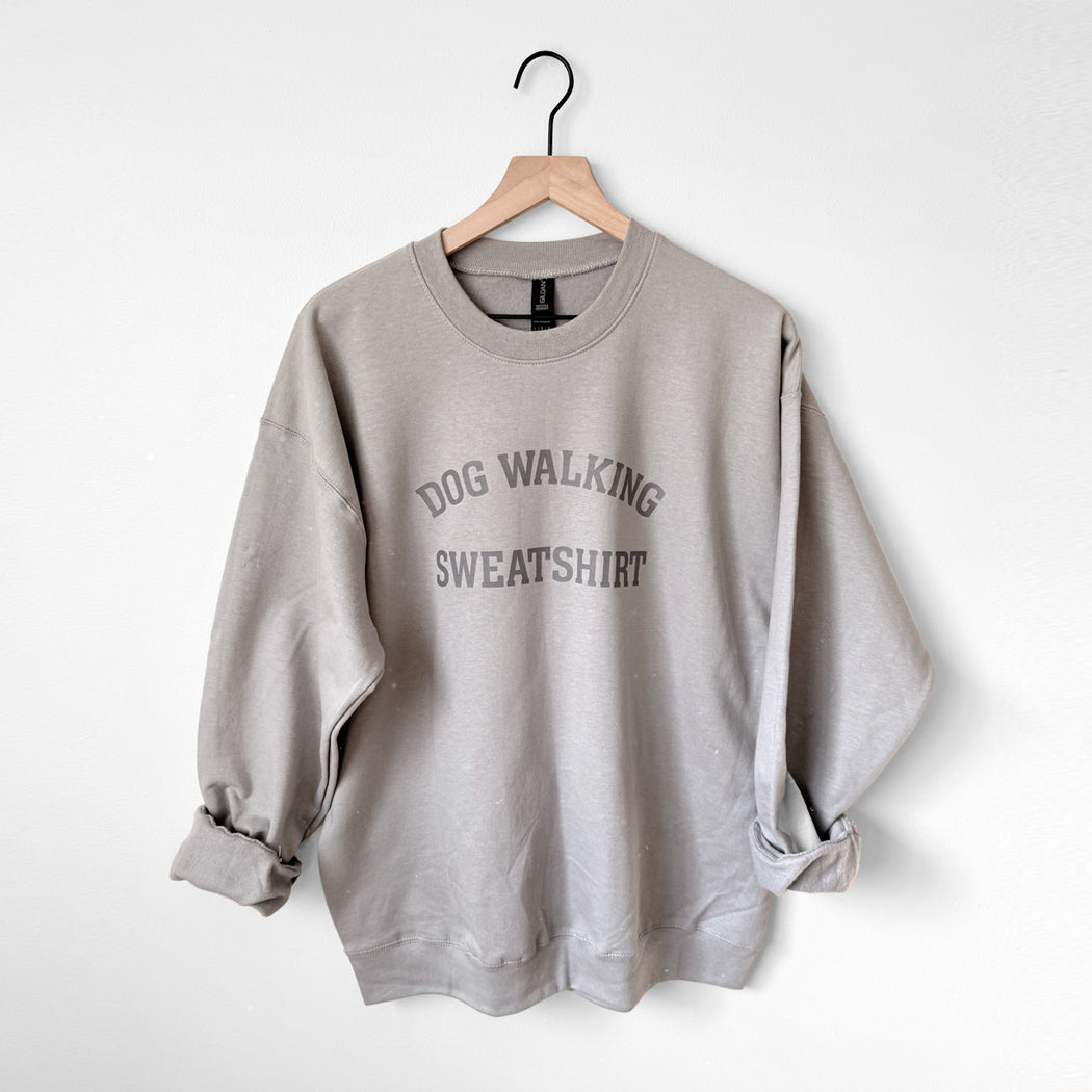 Gray sweatshirt with 'DOG WALKING SWEATSHIRT' text on a hanger against a white background