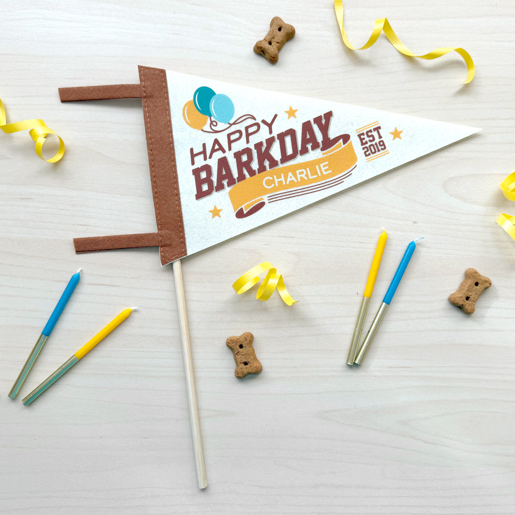 Dog birthday party banner with candles and treats on a light background