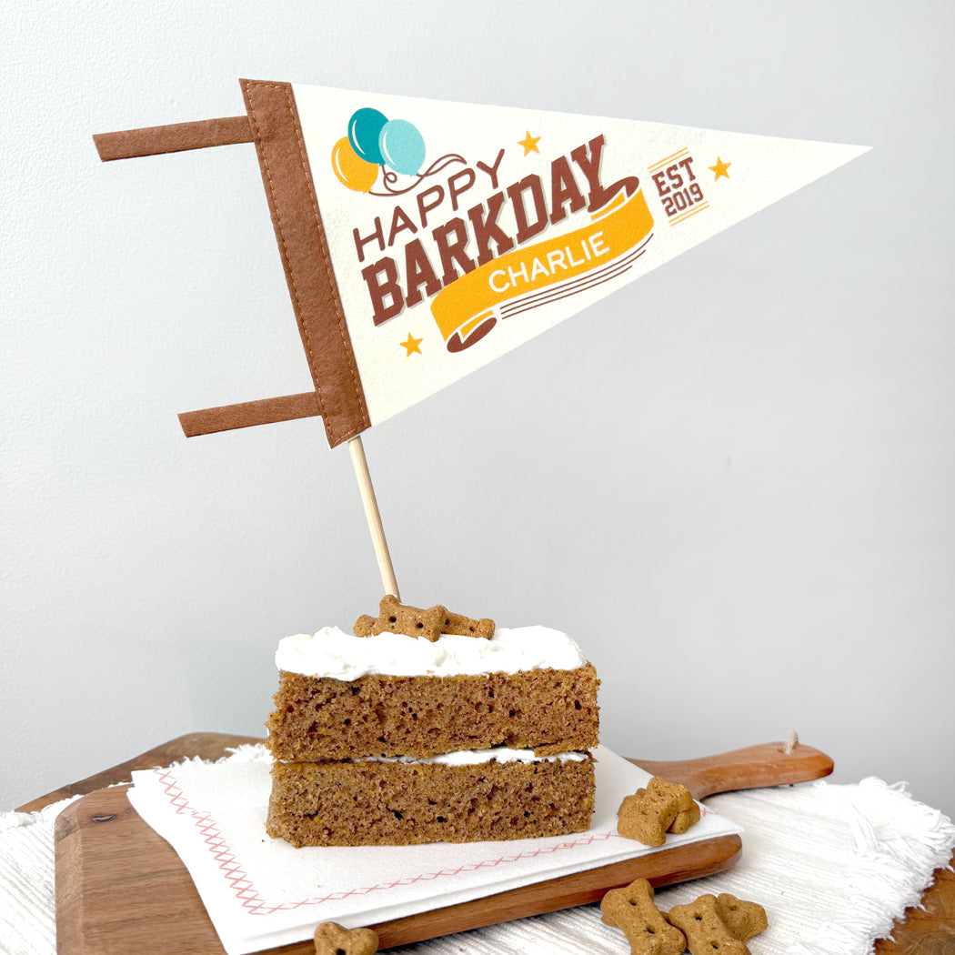 Dog birthday cake with a 'Happy Barkday' flag on a white background