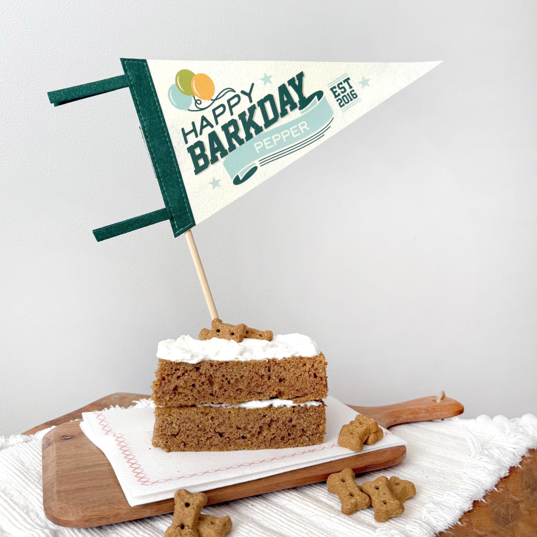 Dog birthday cake with 'Happy Barkday' flag on a wooden board