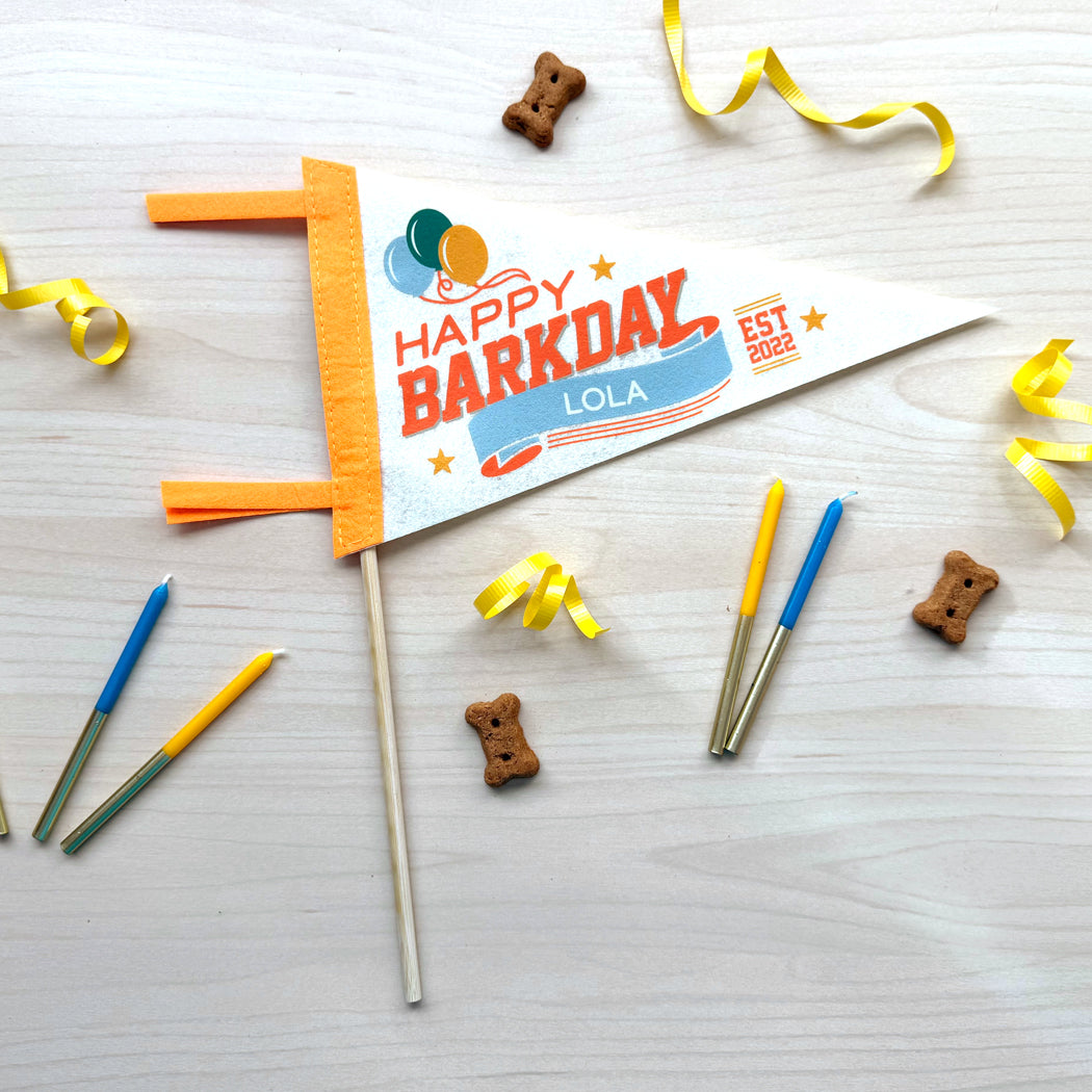 Dog birthday banner with candles and treats on a wooden surface
