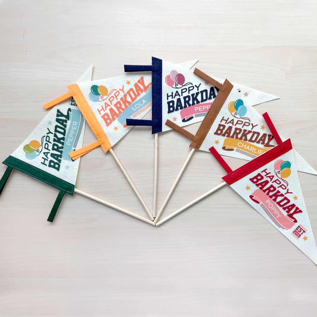 Set of 'Happy Barkday' party flags on sticks against a light background