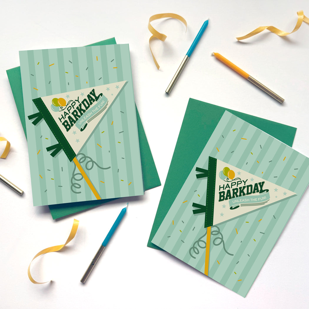 Two 'Happy Barkday' greeting cards with ribbons and pens on a white background