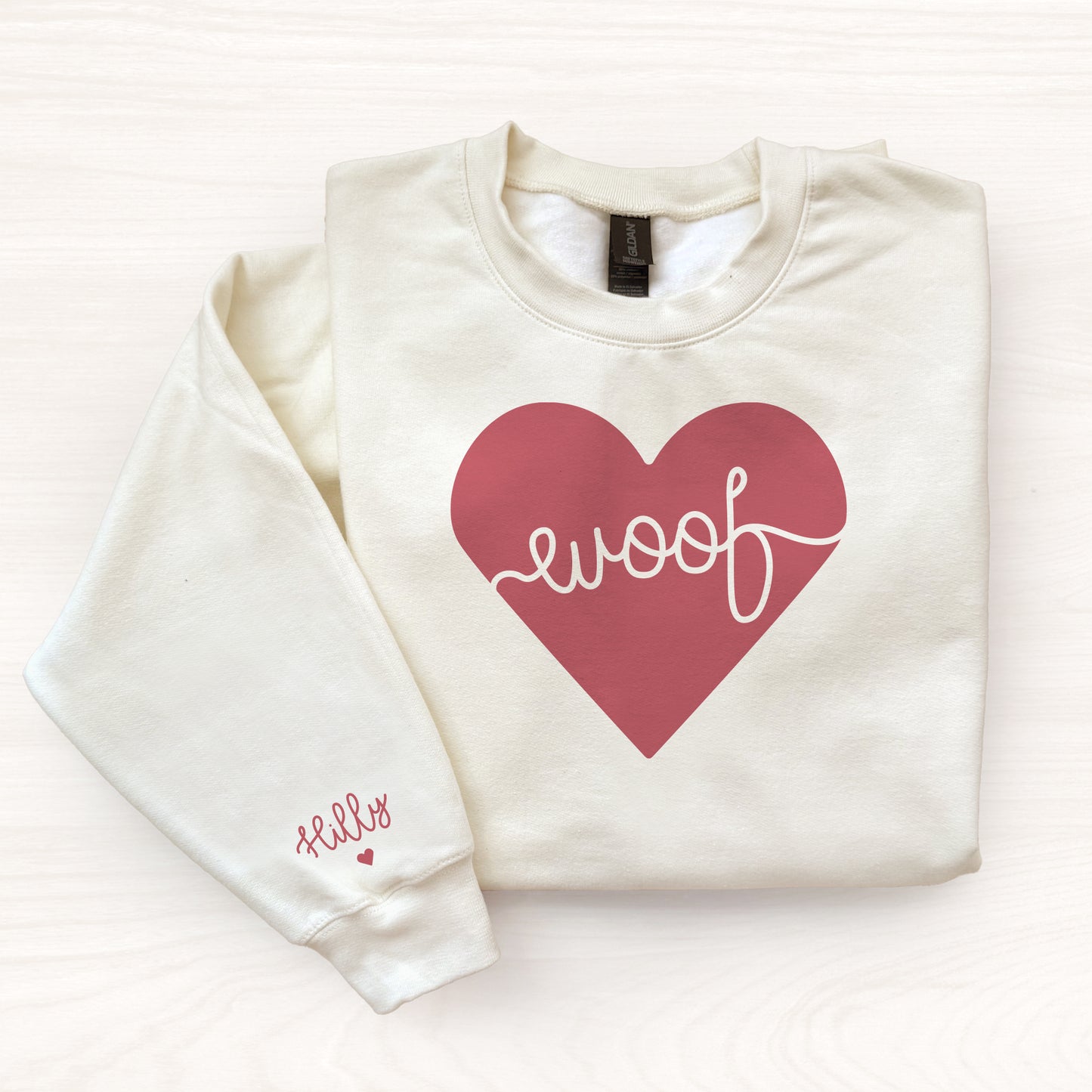 Off whtie sweatshirt with a red heart and 'woof' text on a white background