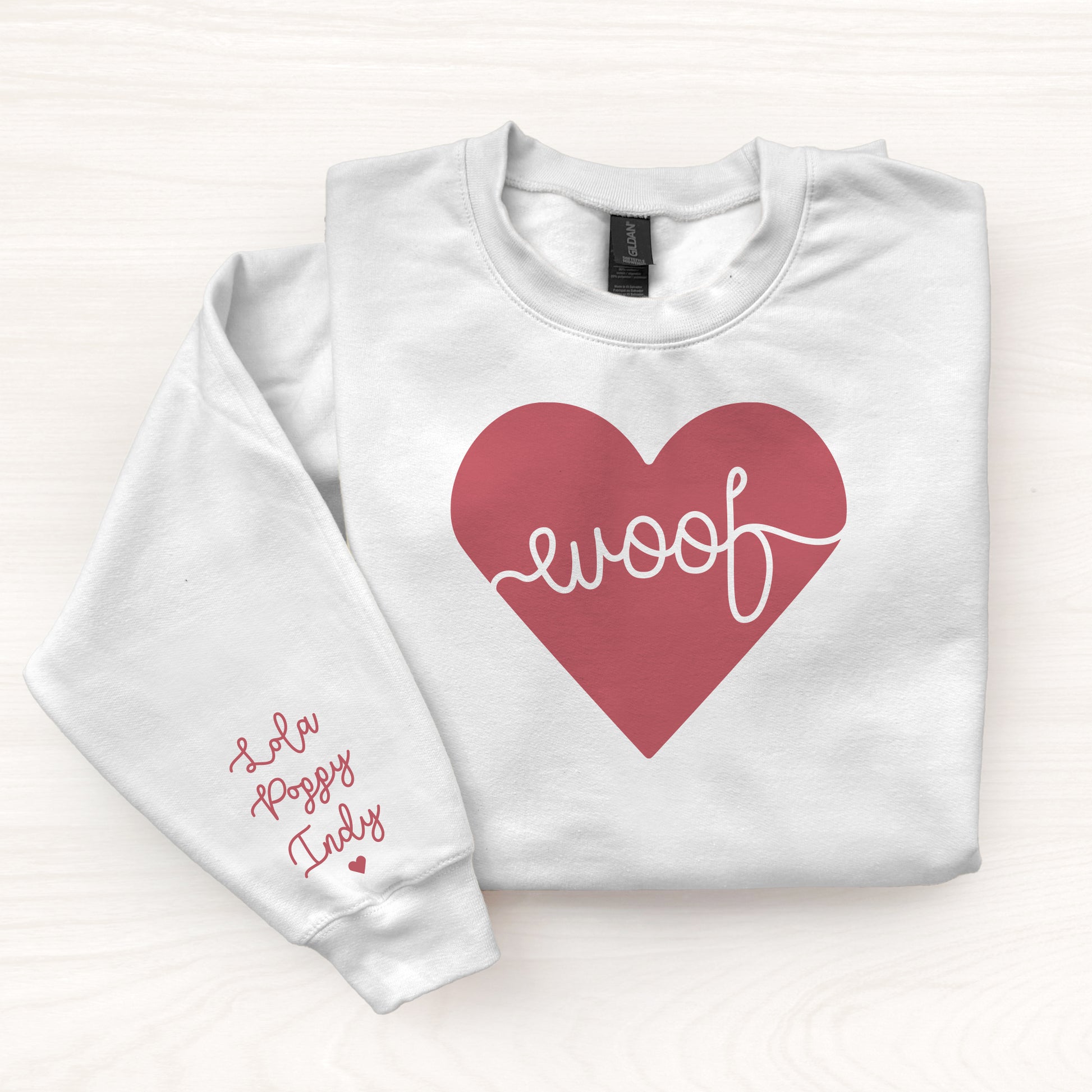 White sweatshirt with a red heart and 'woof' text on a white background