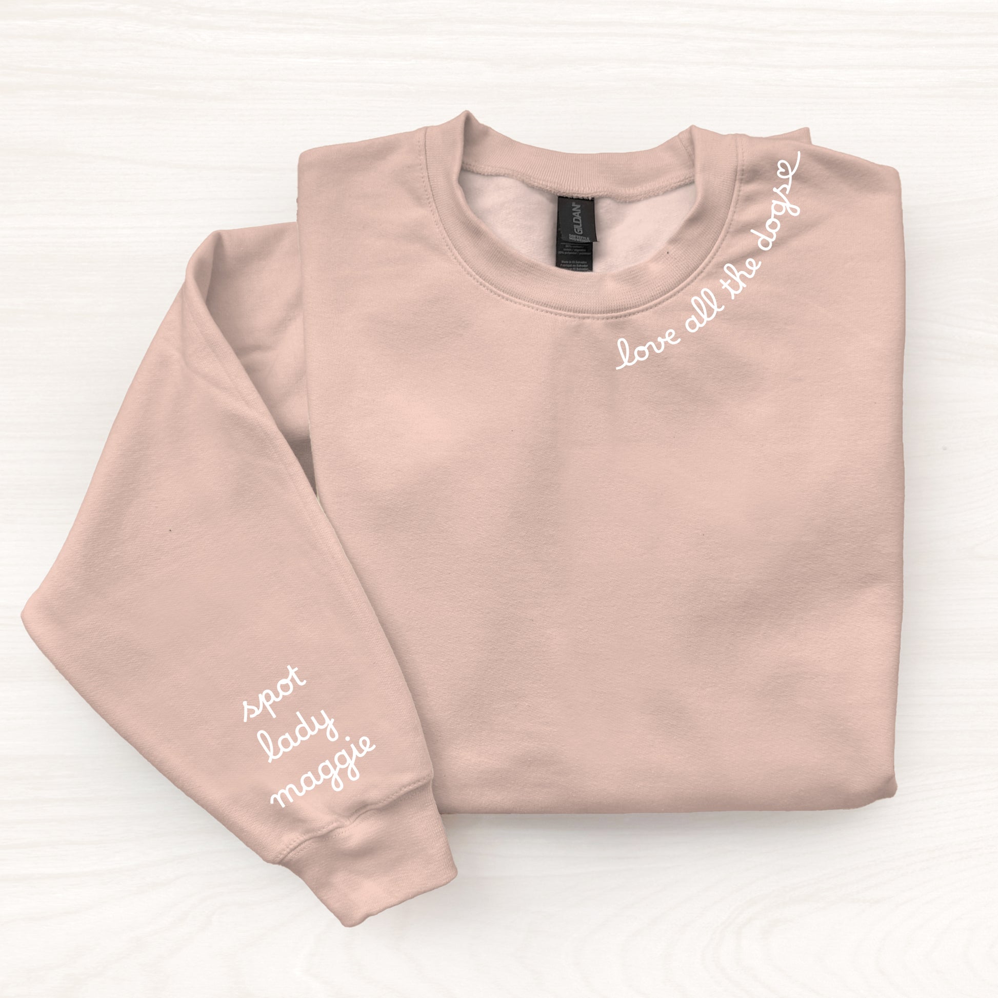Folded blush pink sweatshirt with text on a white background