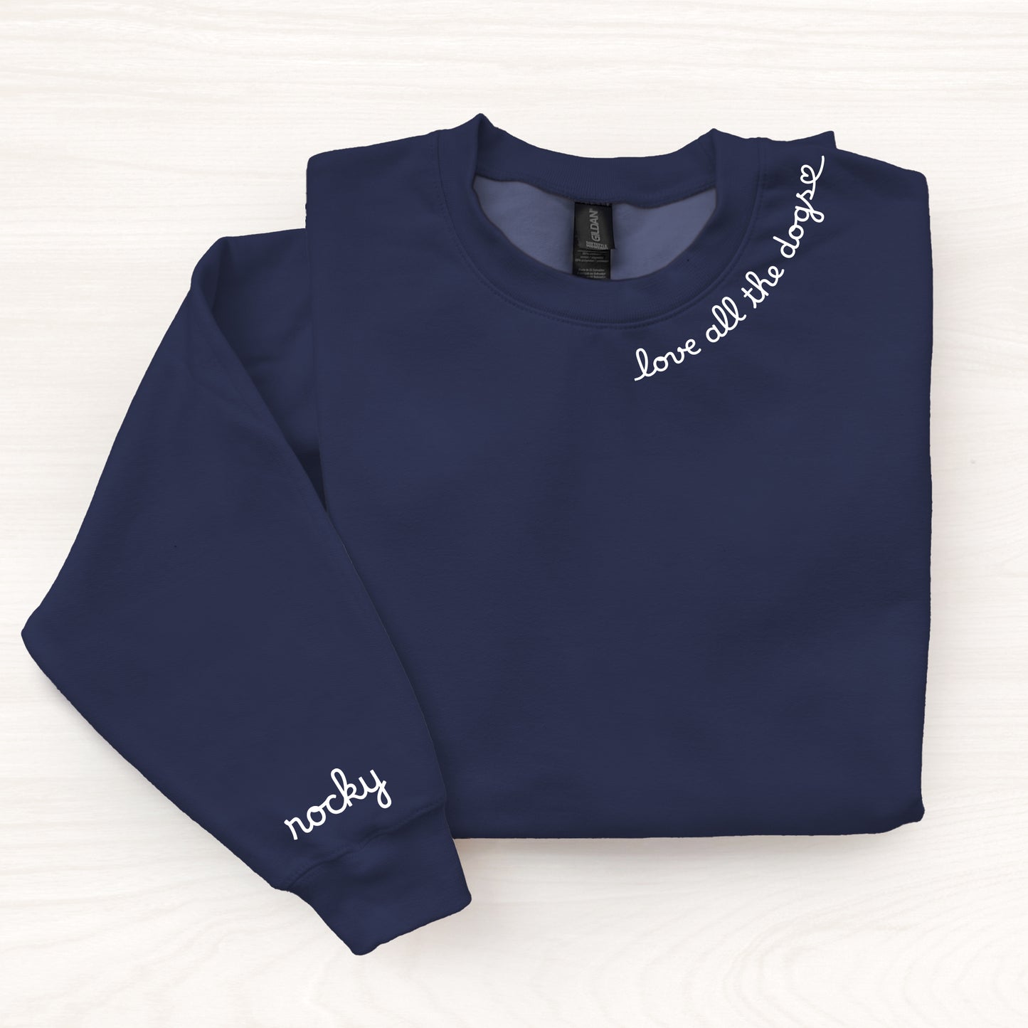 Folded navy blue sweatshirt with text on sleeves against a white background