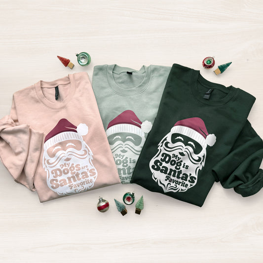 Three sweatshirts with Christmas-themed designs on a light background