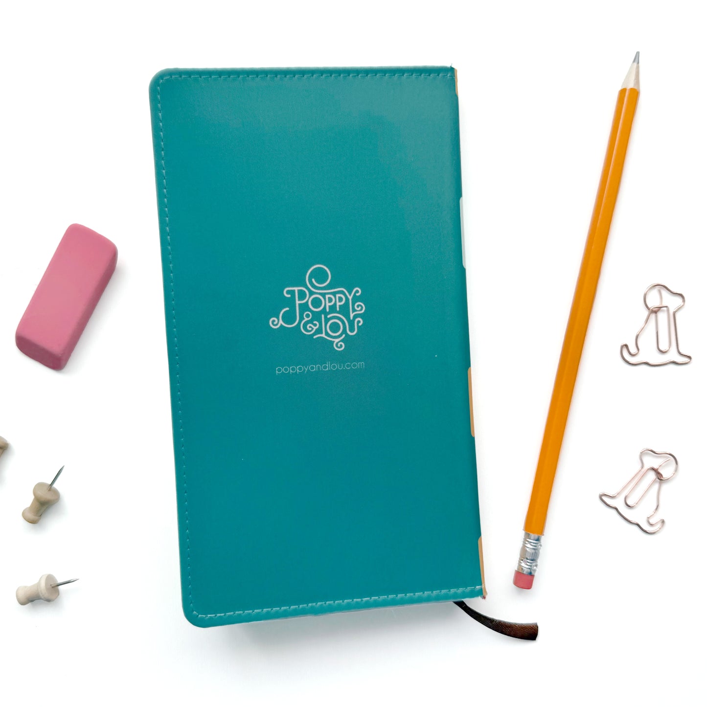Teal notebook with a logo, yellow pencil, pink eraser, and paper clips on a white background