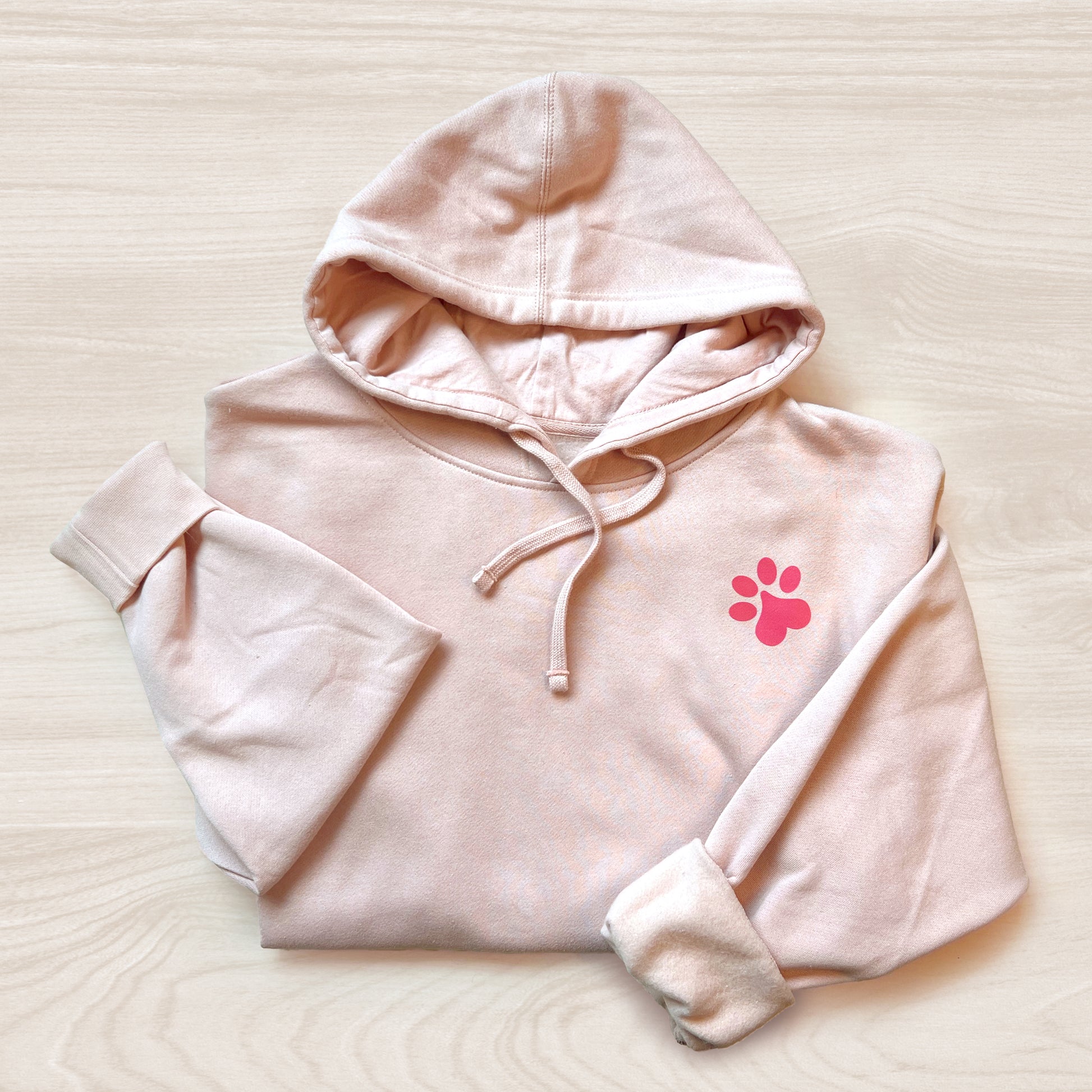 Front view of dusty pink-colored hoodie with paw print design.