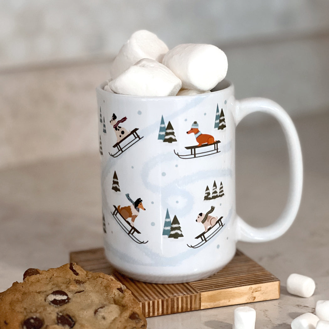 Front view of Dog Sledding Winter Mug featuring illustrated dogs sledding through a snowy landscape.
