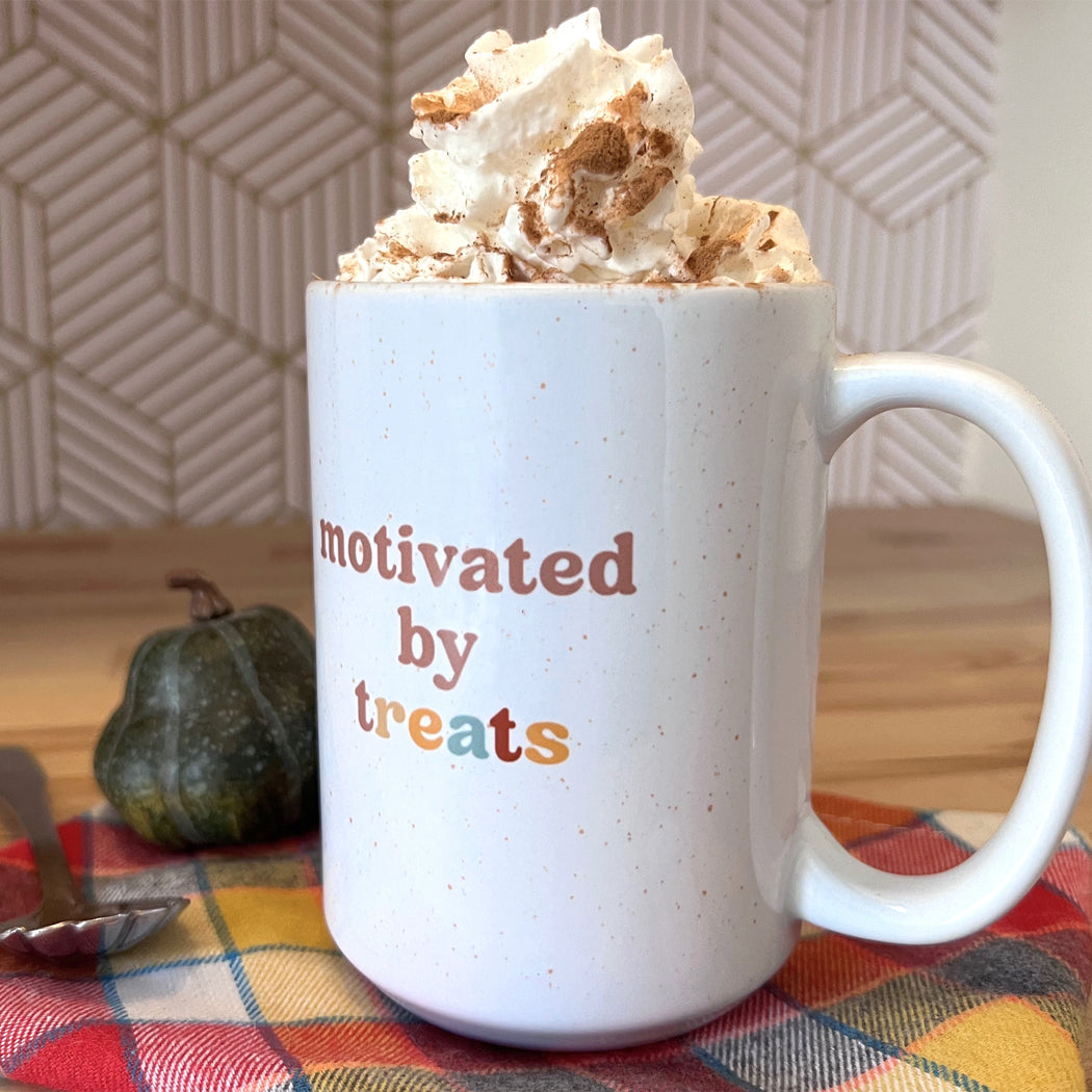 White ceramic mug with ‘Motivated by Treats’ text – perfect gift for dog owners.
