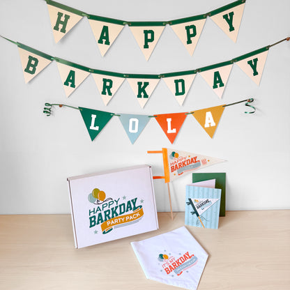 Dog-themed birthday party supplies including a banner, cards, and a box on a wooden surface.