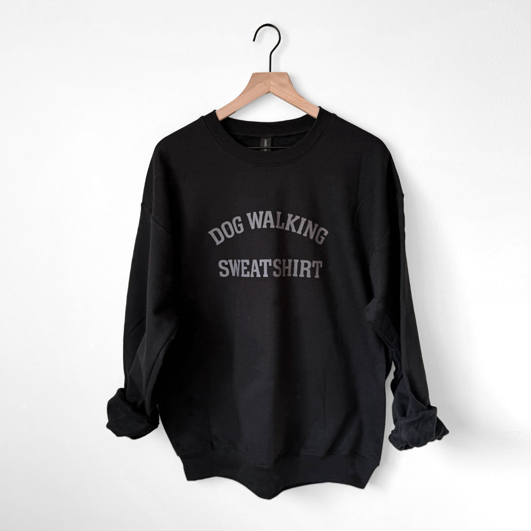Black sweatshirt with 'Dog Walking Sweatshirt' text on a hanger against a white background