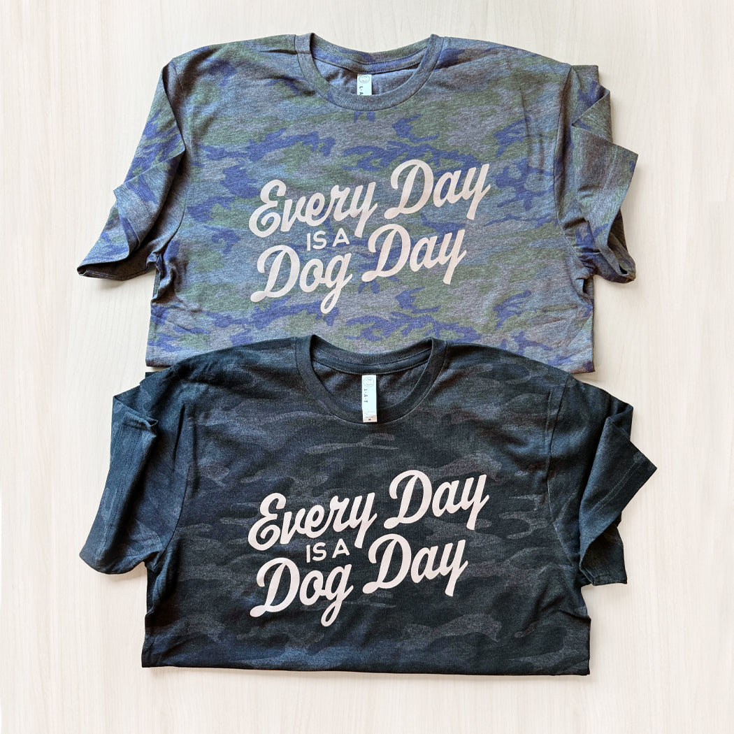 Two t-shirts with 'Every Day is a Dog Day' text on a light wooden surface.