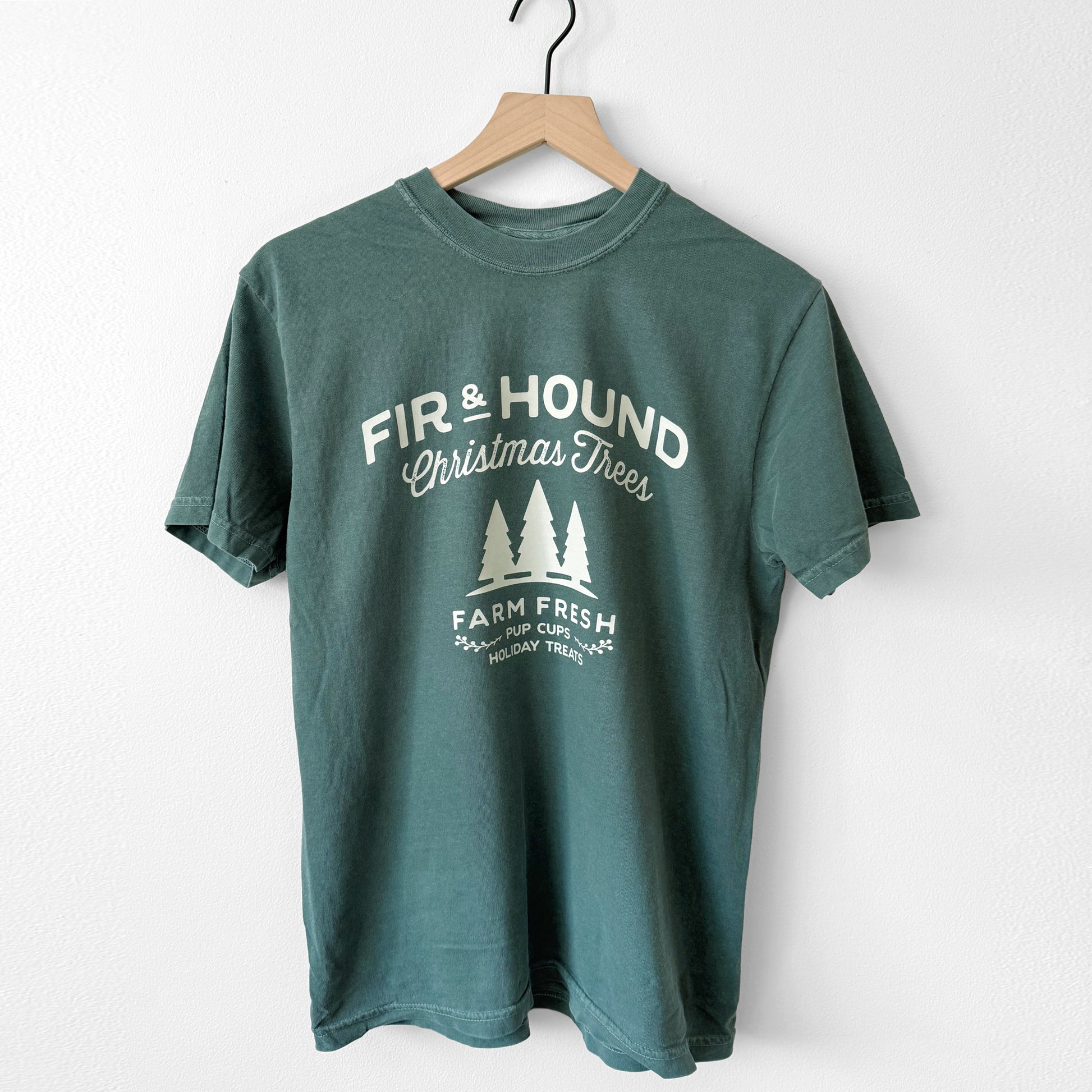 Green t-shirt with white text and graphics on a wooden hanger against a white background
