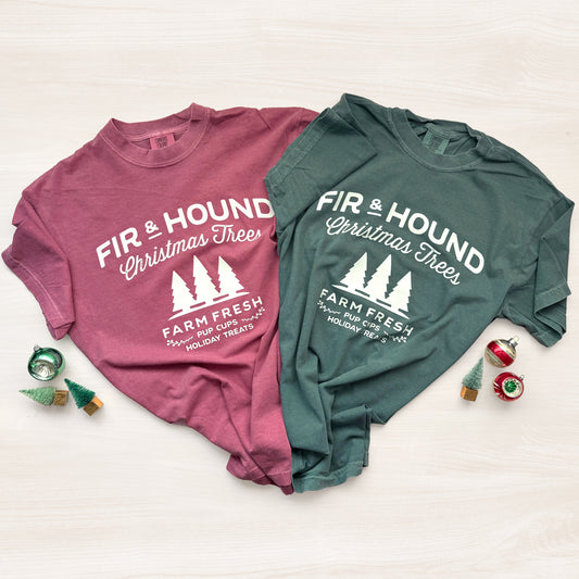 Two t-shirts, one pink and one green, with 'Fir & Hound Christmas Trees' text on a white background.