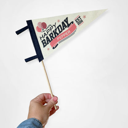 Hand holding a small flag with 'Happy Barkday Pepper' text on a white background