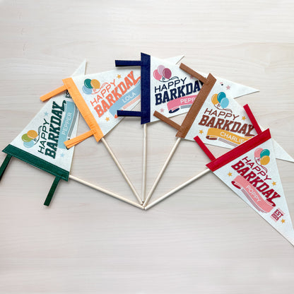 Set of 'Happy Barkday' party flags on sticks against a light background