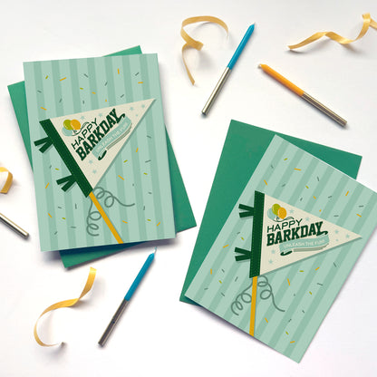Two 'Happy Barkday' greeting cards with ribbons and pens on a white background