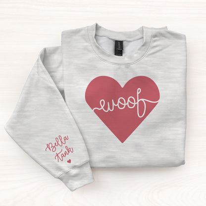 Folded gray sweatshirt with a red heart and 'woof' text on a white background