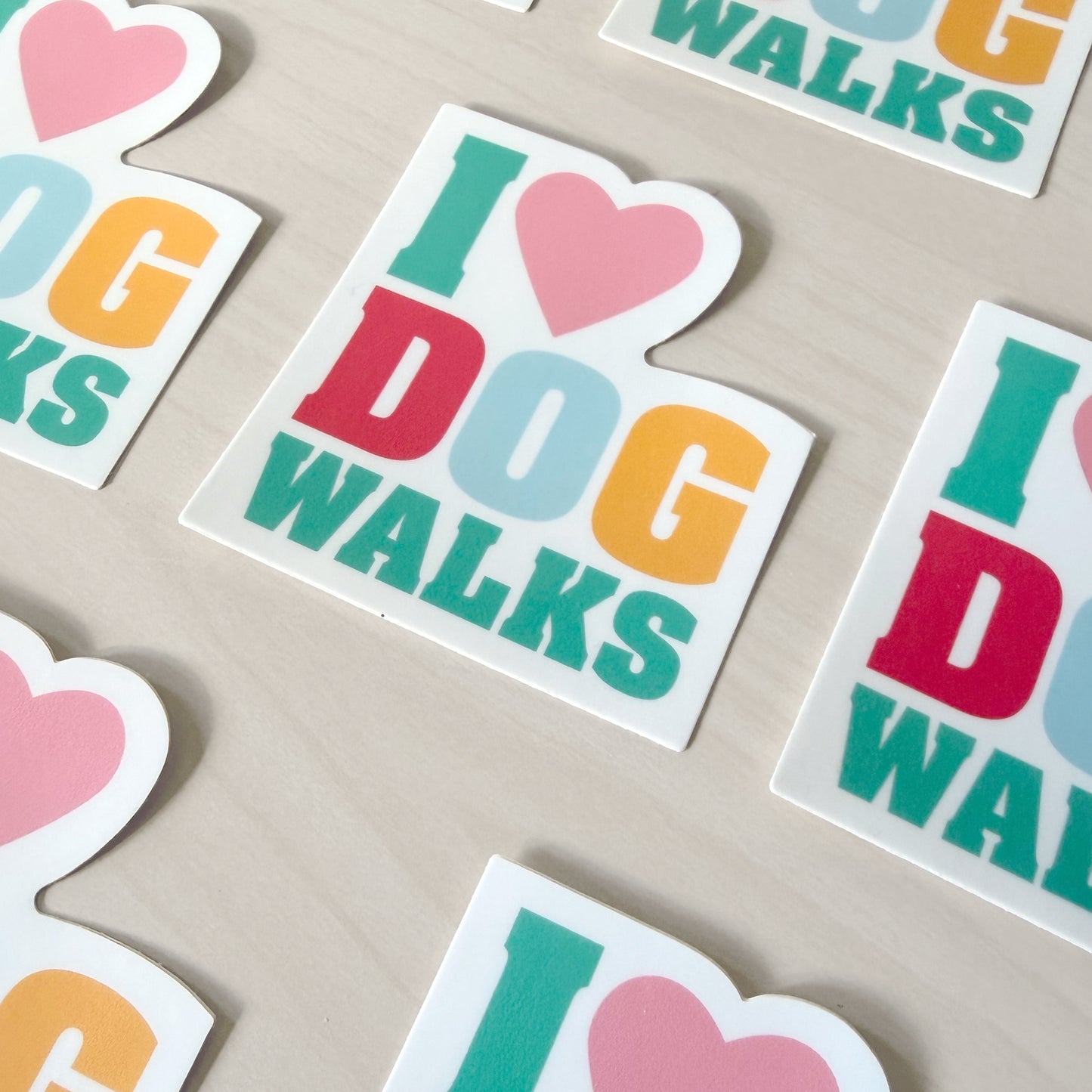 Colorful 'I ❤️ DOG WALKS' stickers on a beige surface