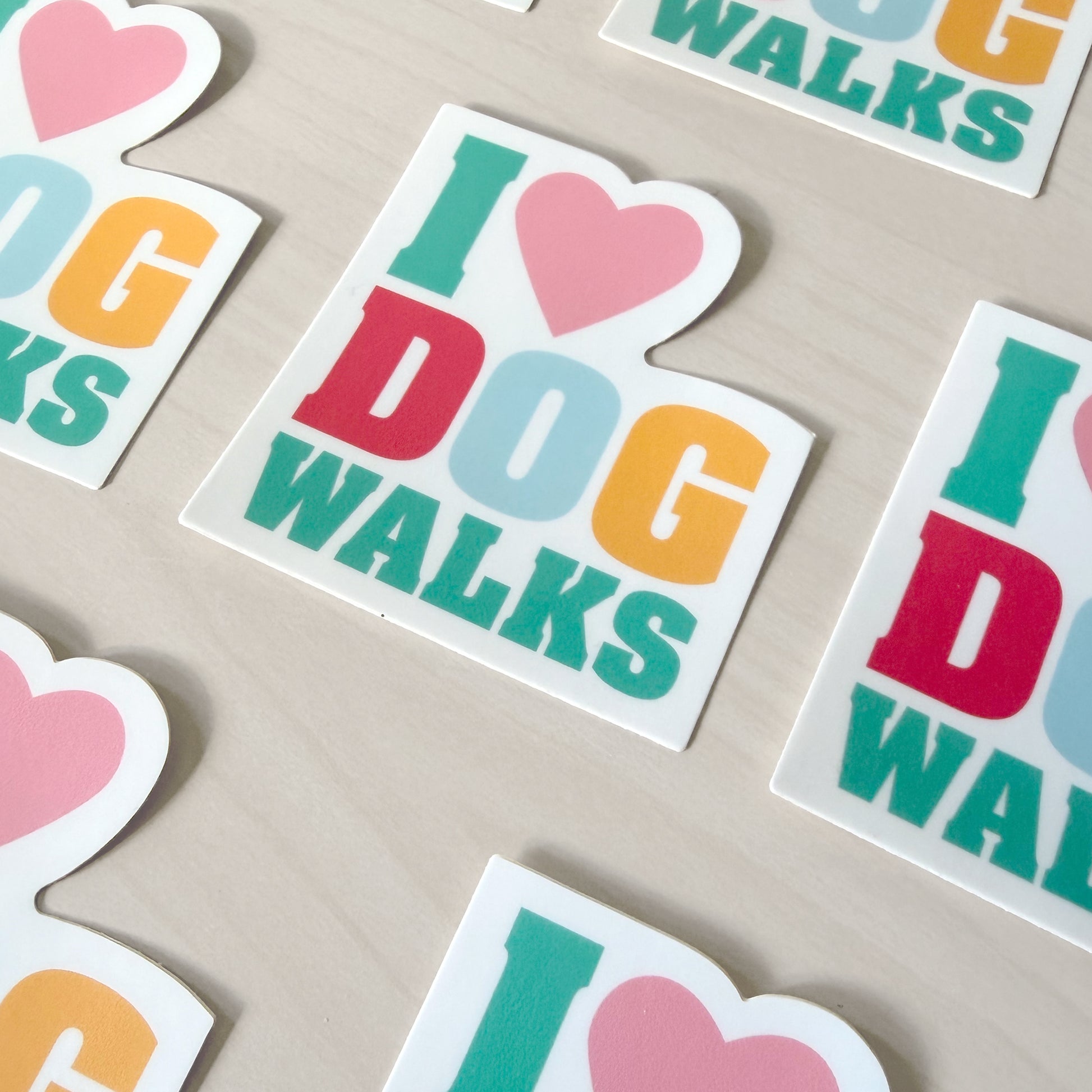 Colorful 'I ❤️ DOG WALKS' stickers on a beige surface
