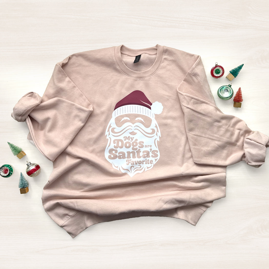 Dusty Rose sweatshirt with Santa graphic and text on a light background with Christmas decorations.