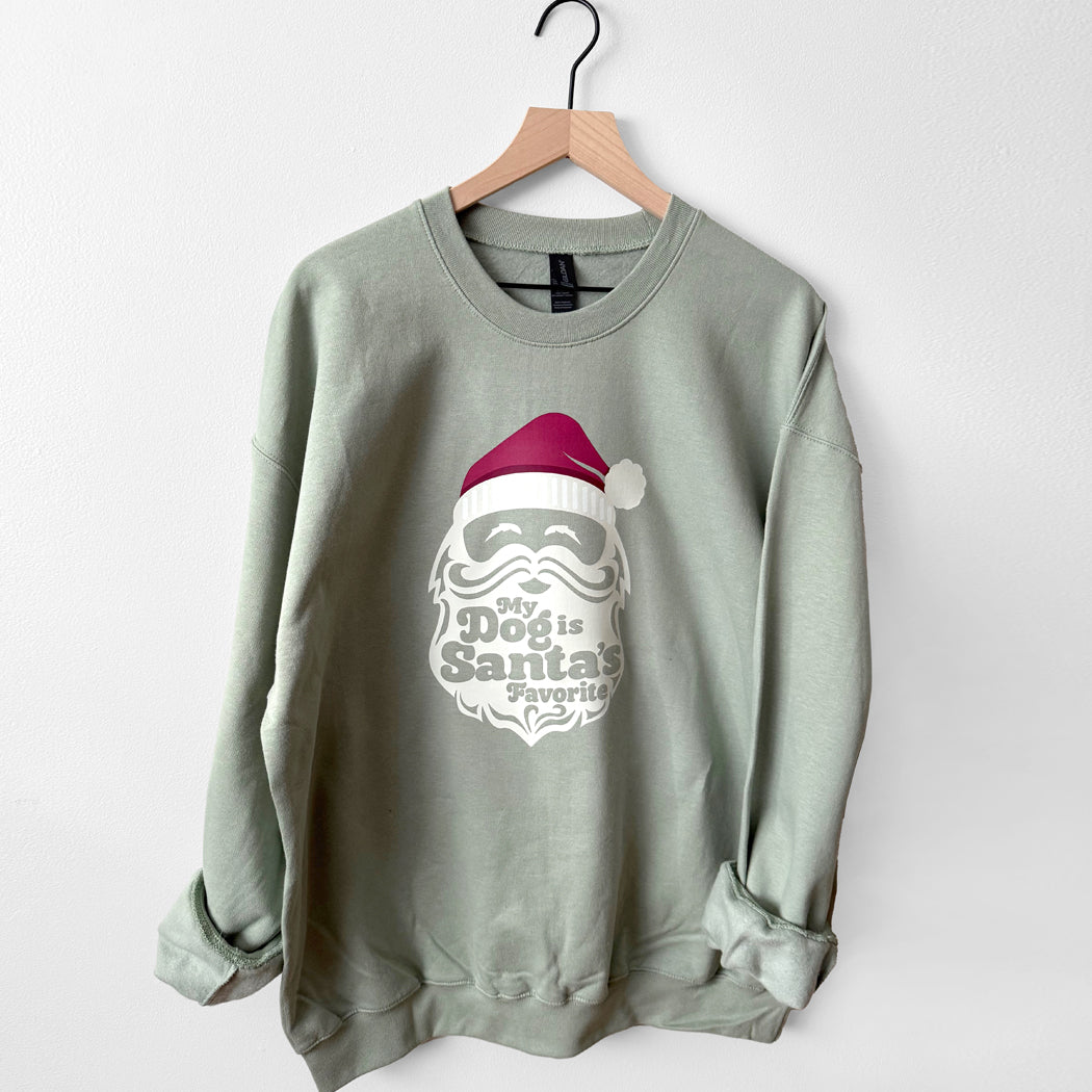 Sage sweatshirt with a graphic design of a face wearing a Santa hat and text on a white background