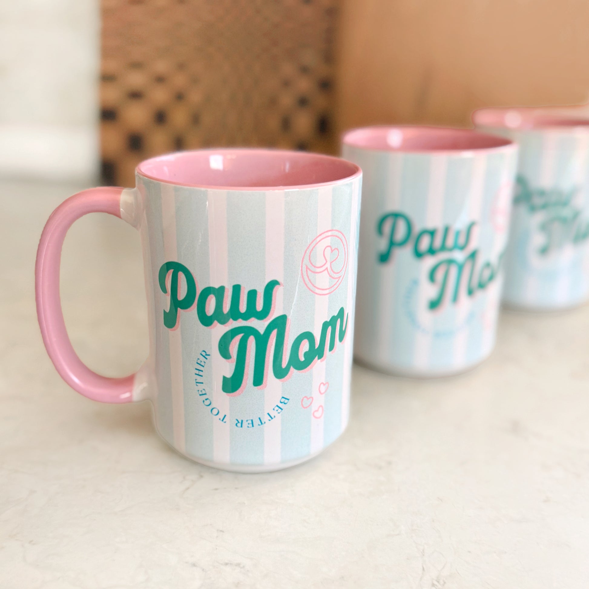 Mugs with 'Paw Mom' text on a light surface
