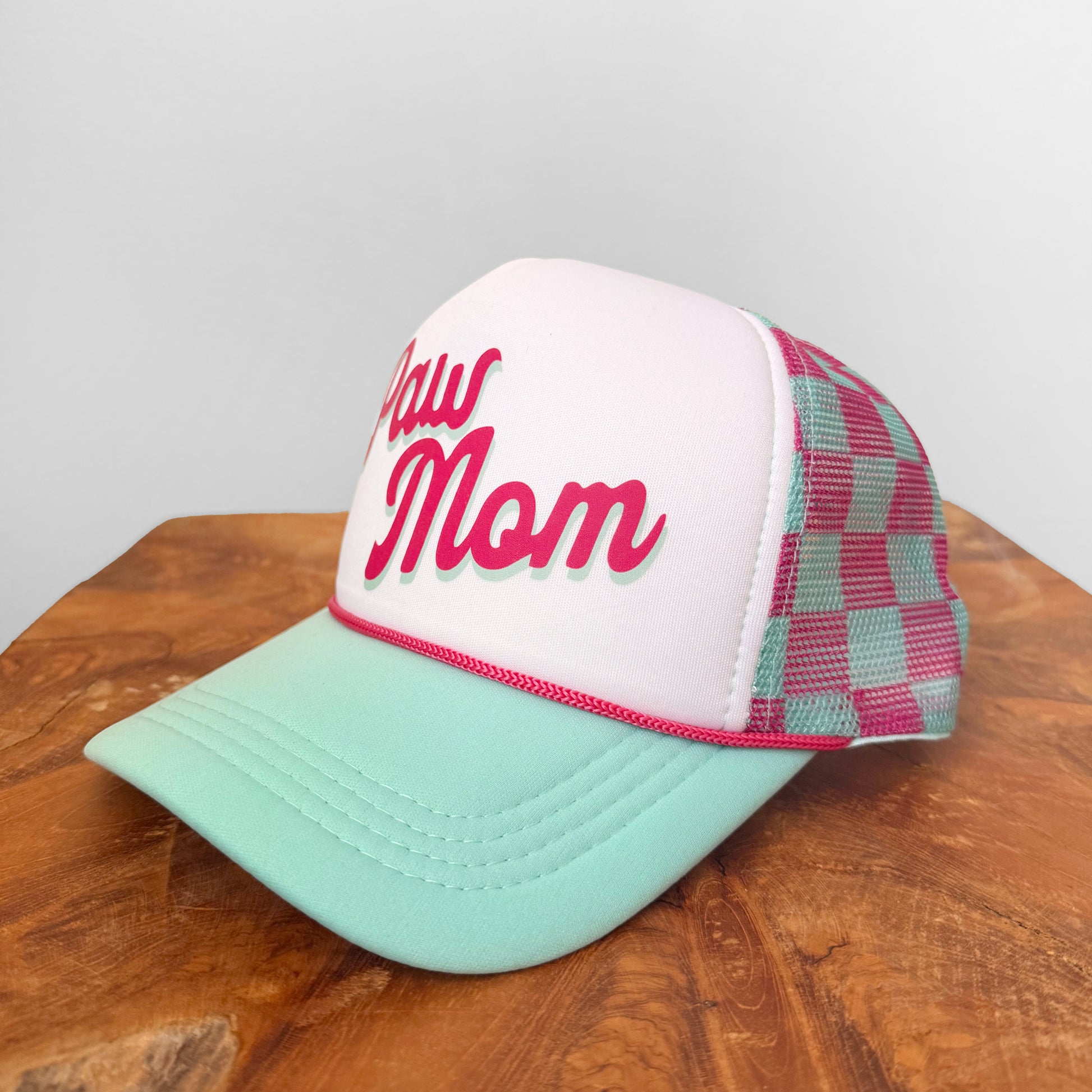 Trucker hat with 'Raw Mom' text on a wooden surface