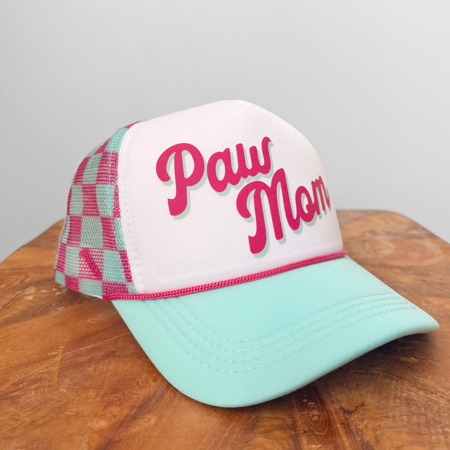 Trucker hat with 'Paw Mom' text on a wooden surface