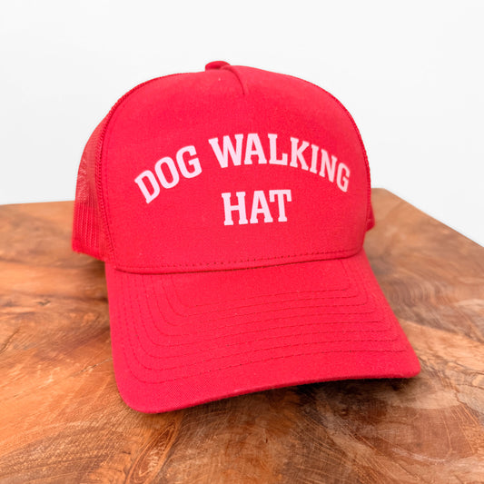 Red trucker hat that says "Dog Walking Hat" in light pink.