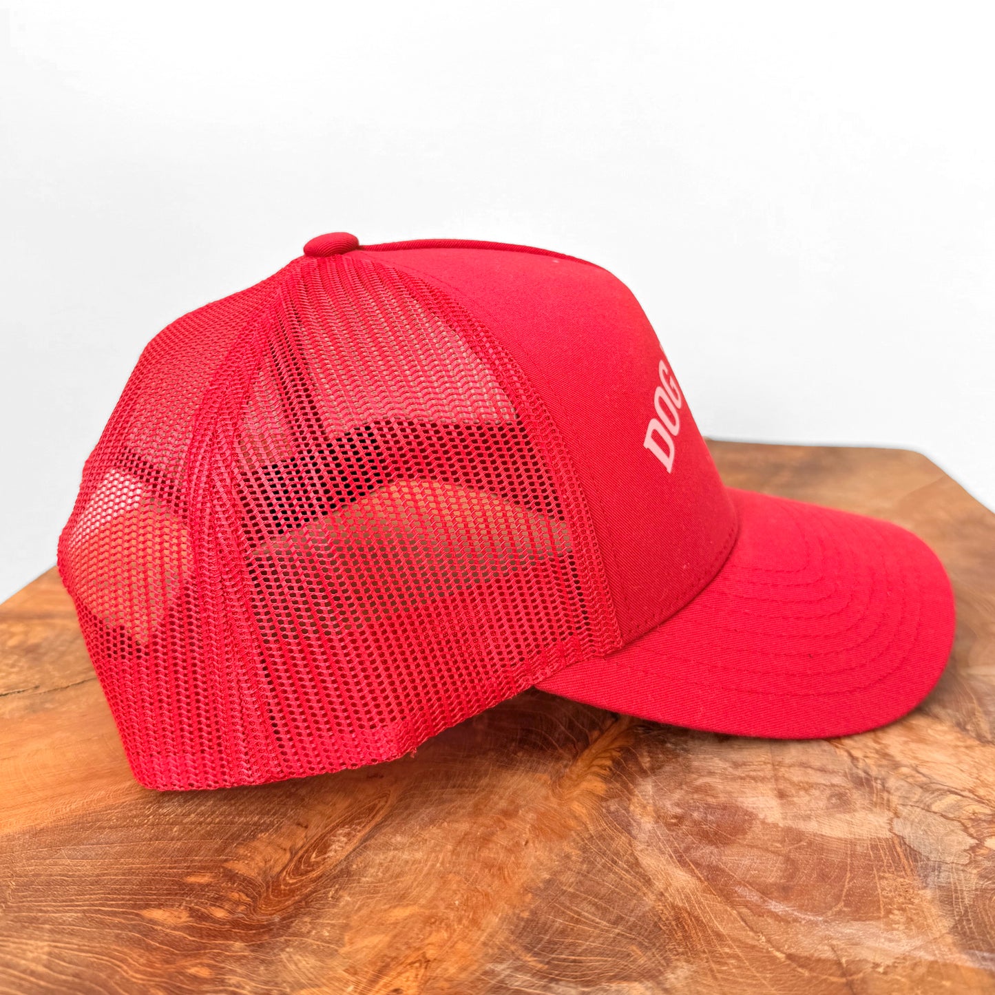 Red mesh cap on a wooden surface with a white background