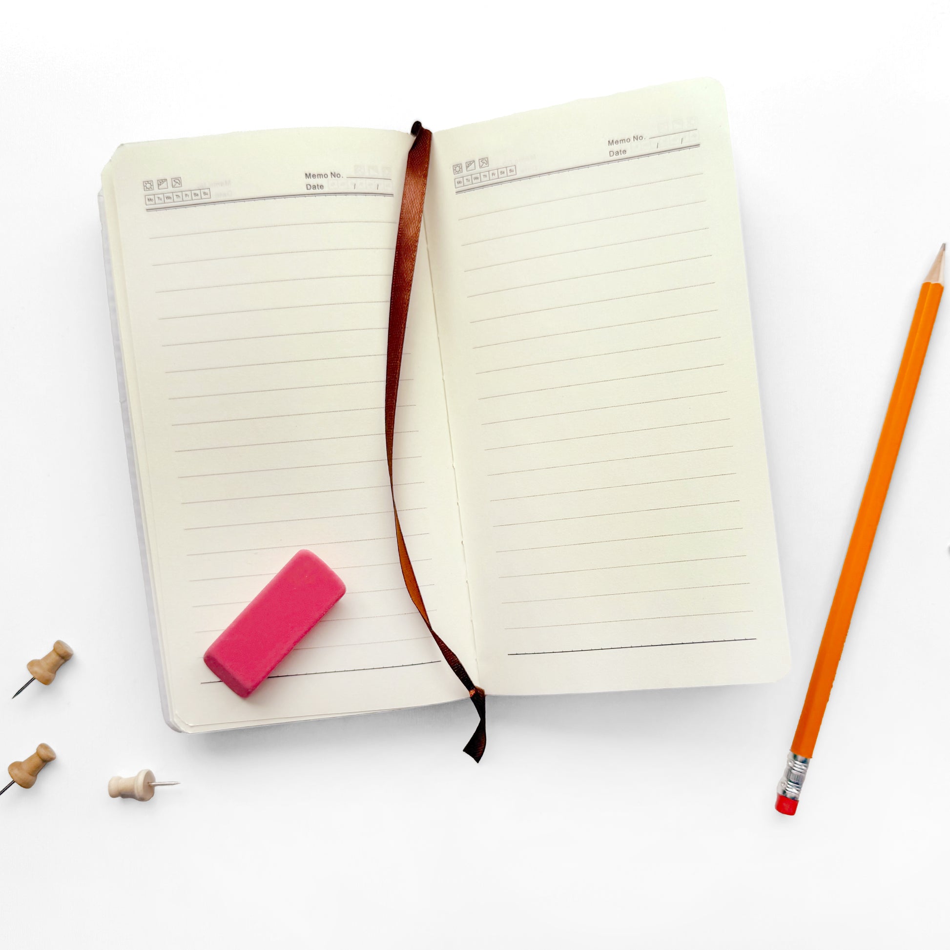 Open notebook with a pink eraser and orange pencil on a white background