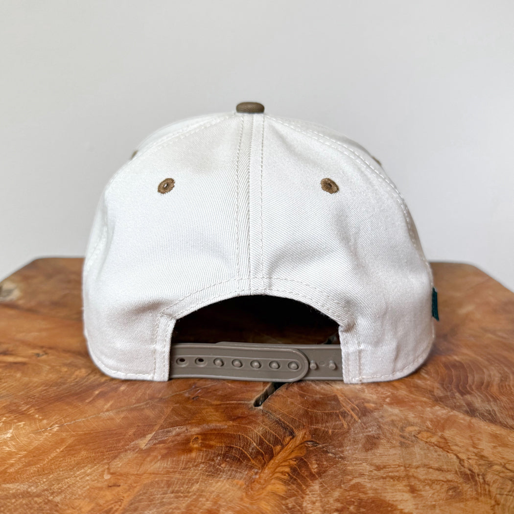 White cap with a brown brim on a wooden surface