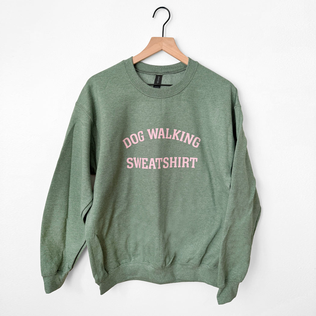 Green sweatshirt with 'Dog Walking Sweatshirt' text on a hanger against a white background