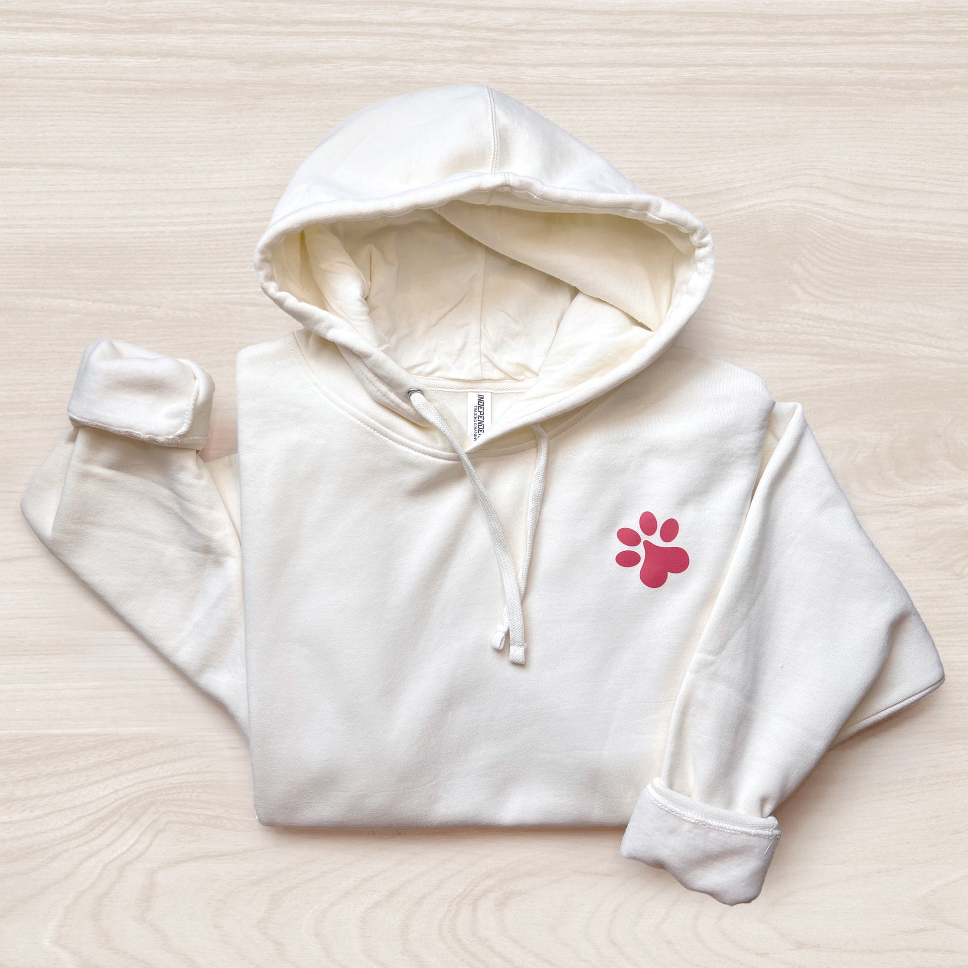 Front view of bone-colored hoodie with paw print design.