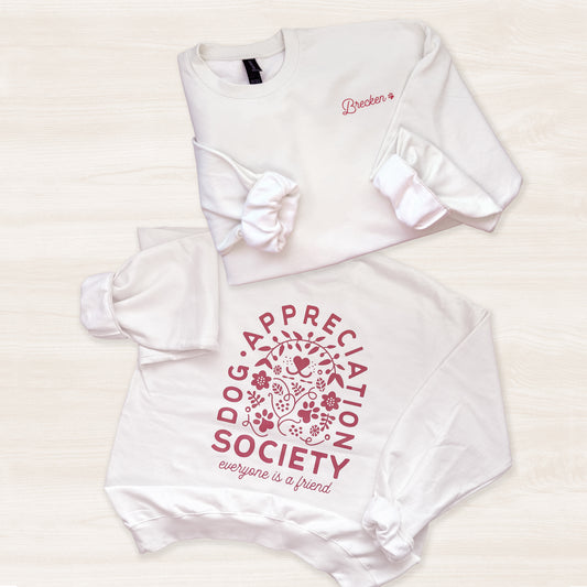 White sweatshirt with 'Appreciation Dog Society' text and floral design on a light background