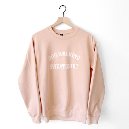Pink sweatshirt with 'DOG WALKING SWEATSHIRT' text on a hanger against a white background
