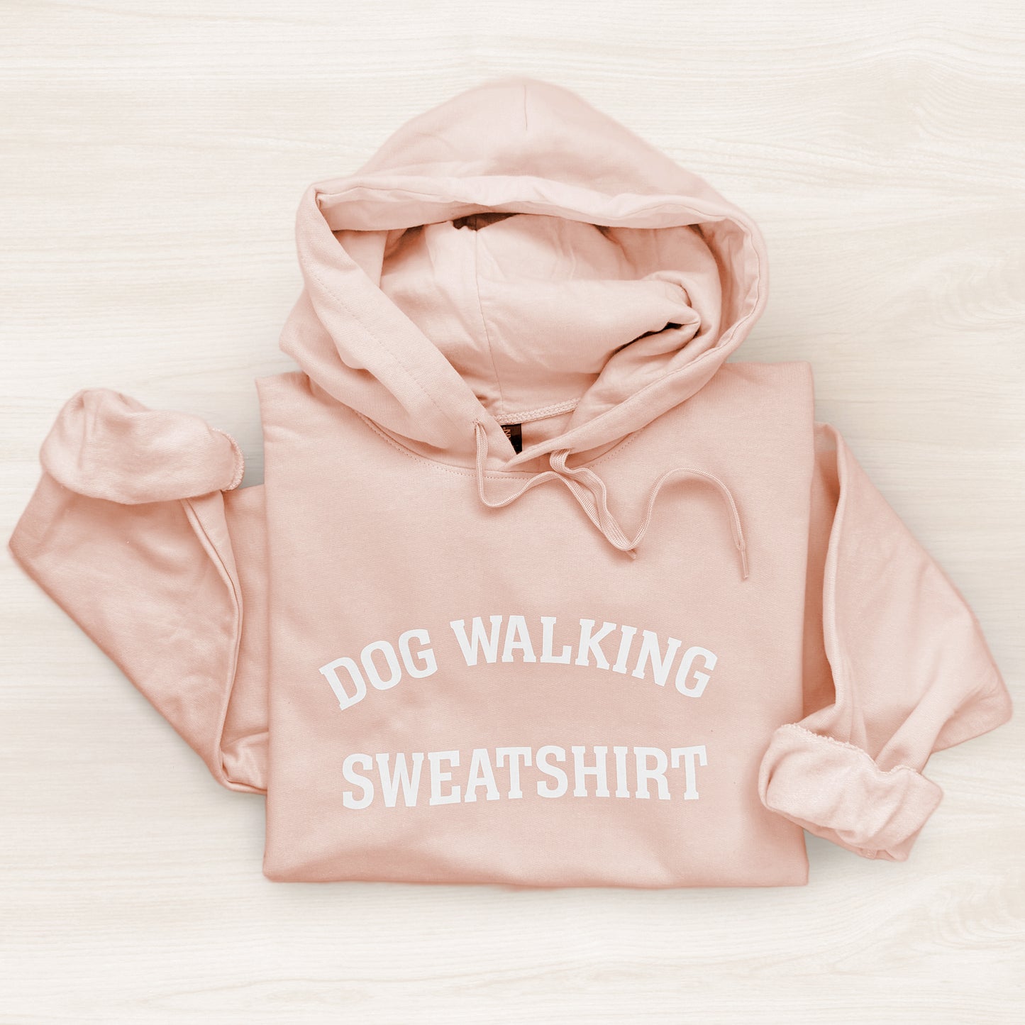 Pink hoodie with 'DOG WALKING SWEATSHIRT' text on a light background