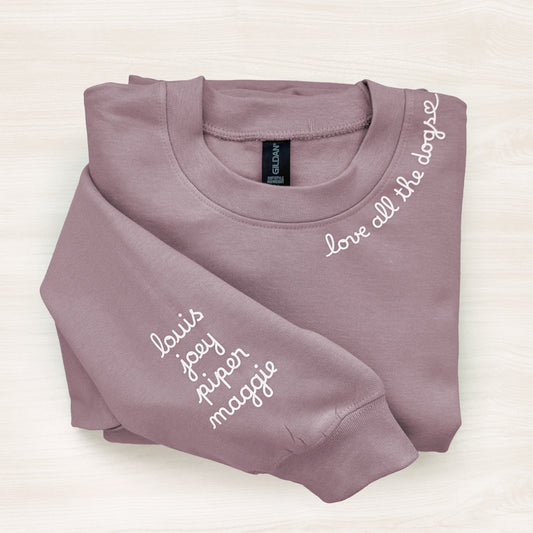 Folded mauve sweatshirt with names printed on a white background