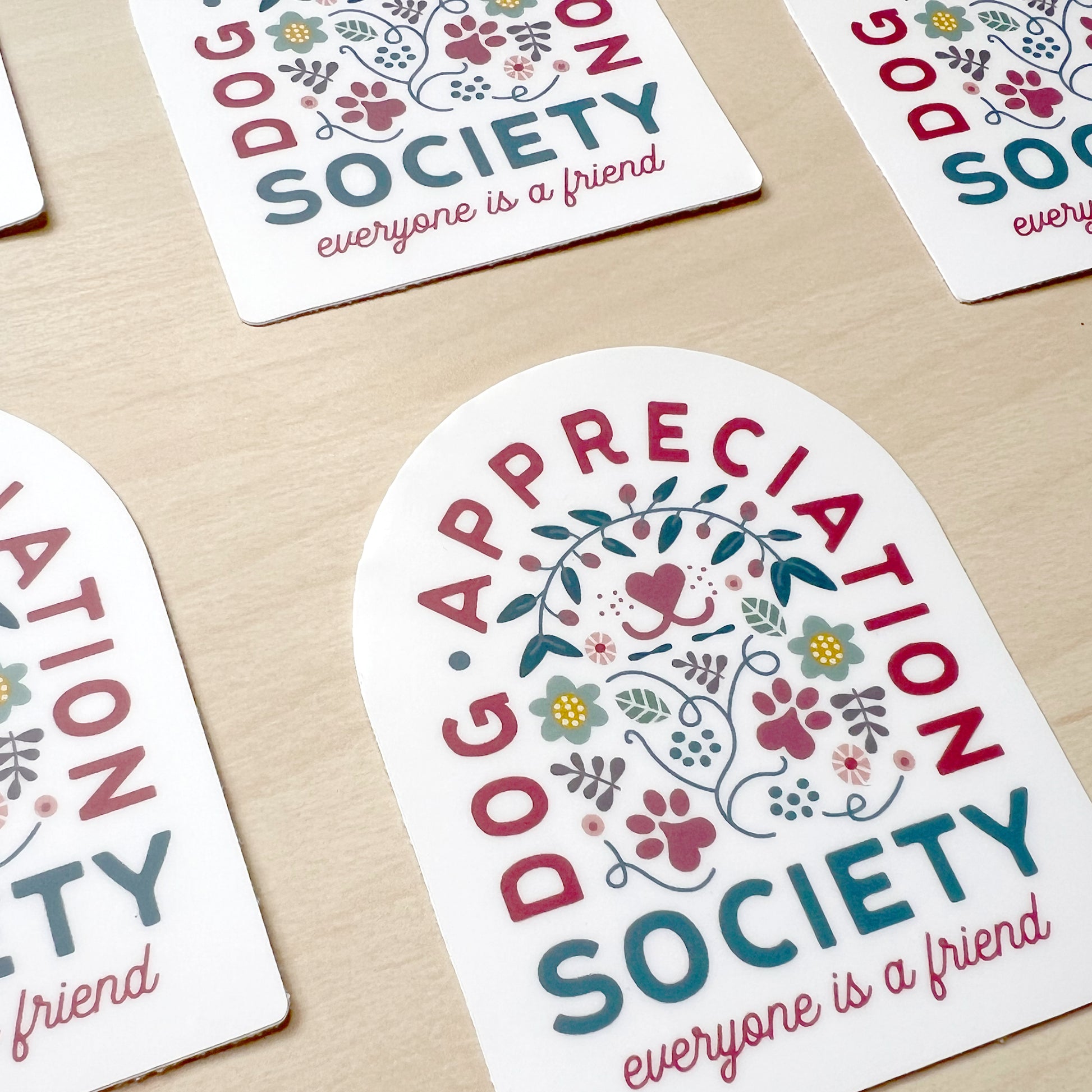 Front view of Dog Appreciation Society Sticker with dog nose, paws, flower, leaves, and hearts design.