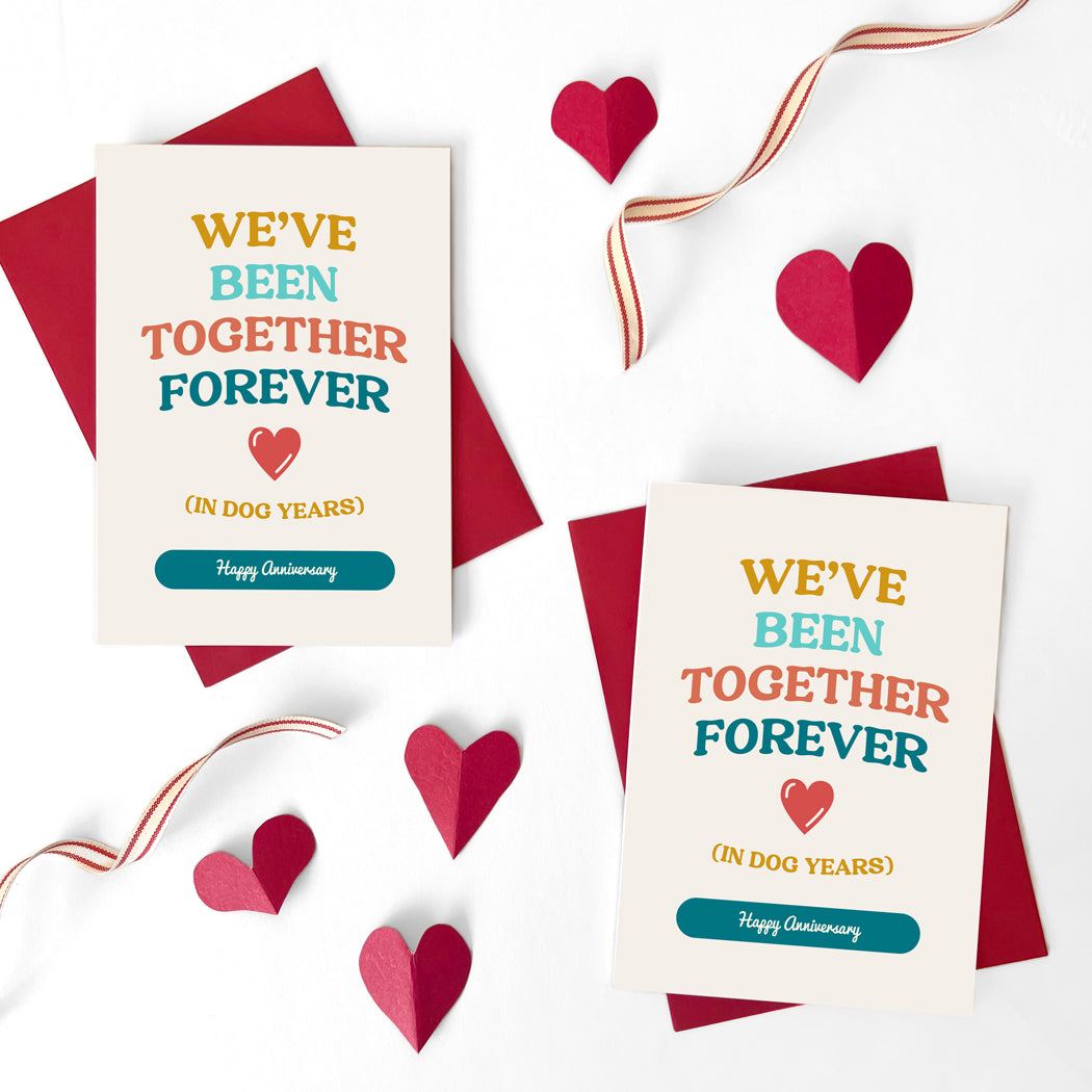 Front view of Dog Years Anniversary Card with 'We've Been Together Forever (In Dog Years). Happy Anniversary' message" and "Red envelope accompanying the Dog Years Anniversary Card.